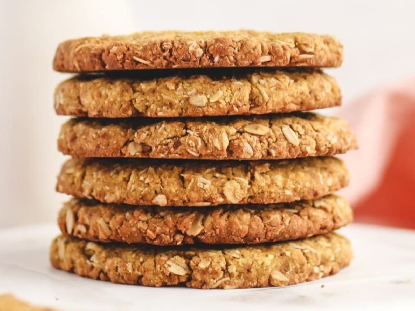 A stack of six whole-oat cookies, baked golden, on a pale marble surface